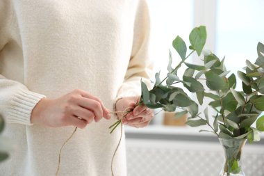 Çiçekçi, çiçekçide okaliptüs dallarından güzel bir buket yapıyor.