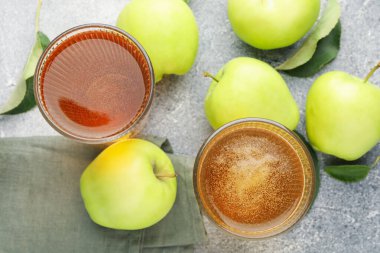 Lezzetli elma şarabı, elmalar ve yapraklar gri desenli masa, düz uzanış