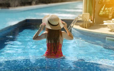 Deniz kıyısındaki havuzda hasır şapkalı kız.