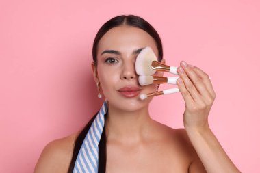 Pembe bir arka plan üzerinde makyaj fırçaları ile güzel kadın