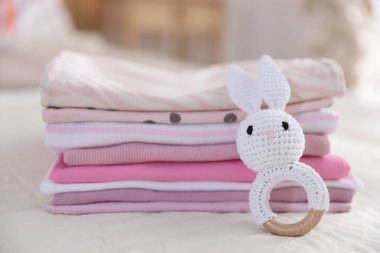 Temiz bebek kıyafetleri ve yatak örtüleri iç mekanda, yakın plan.