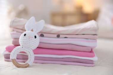 Temiz bebek kıyafetleri ve yatak örtüleri iç mekanda, yakın plan.