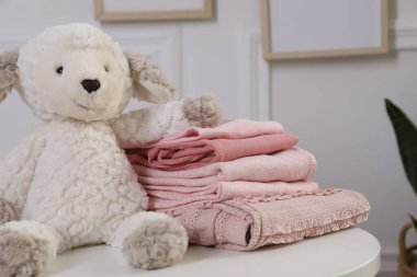 İçerideki beyaz masada temiz bebek kıyafetleri yığını, yakın plan.