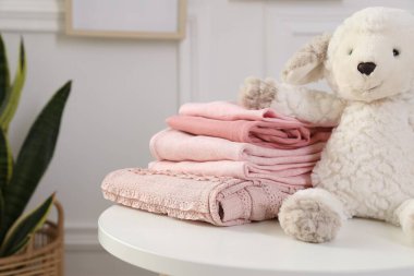 İçerideki beyaz masada temiz bebek kıyafetleri yığını, yakın plan.