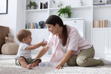 Anne ve tatlı bebeği evde yerde oyuncaklarla oynuyorlar.