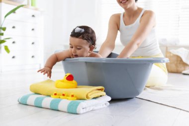 Anne küçük bebeğini evde yıkıyor, yakın plan.