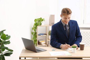 Ofisteki ahşap masada iş planlayıcısı kullanan adam.