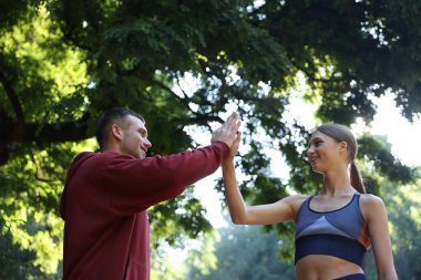 Profesyonel kişisel antrenörü olan genç bir kadın açık havada beşlik çakıyor, düşük açılı.