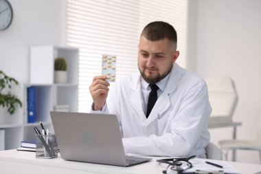 Klinikte bilgisayarla internetten danışmanlık yapan haplı bir doktor.