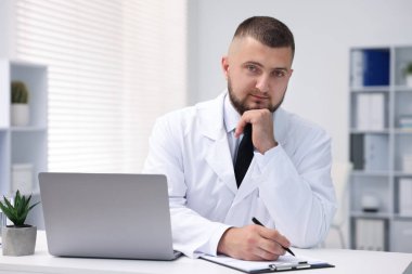 Klinikte dizüstü bilgisayarla çalışan bir doktor. Online tıbbi danışmanlık