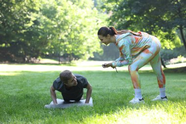 Genç adam profesyonel antrenörle dışarıda egzersiz yapıyor.