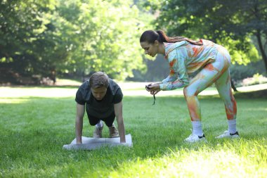 Genç adam profesyonel antrenörle dışarıda egzersiz yapıyor.