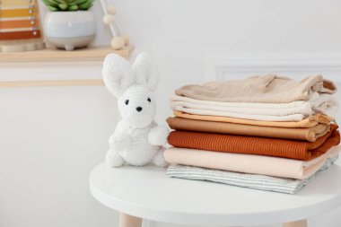 Temiz bebek kıyafetleri yığını ve beyaz masa, kapalı, yakın çekim