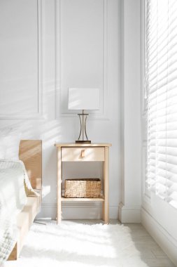 Yatağın yanında lamba olan komodin.