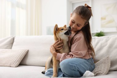 Evdeki kanepede köpeğini kucaklayan tatlı küçük kız, mesaj atmak için yer var. Çocuk ve hayvan