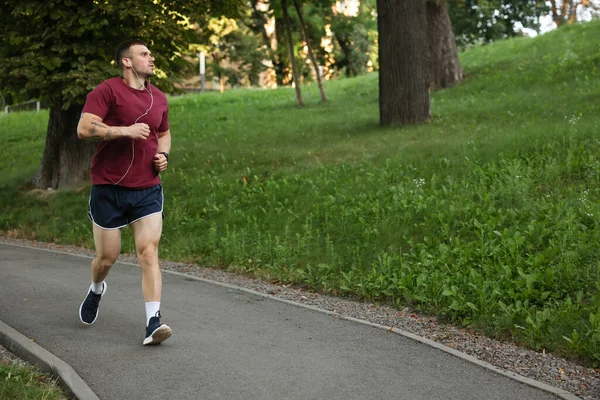 Spor giyimli atletik genç adam dışarıda koşuyor.