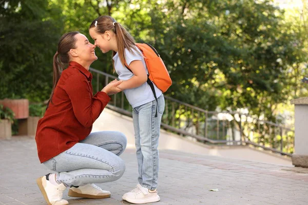 Anne kızını açık havaya, mesaj atmak için okula götürüyor.