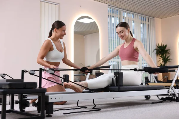 Stüdyoda pilates eğitmeni tarafından yönetilen reformcu kadın üzerinde egzersiz yapıyor.