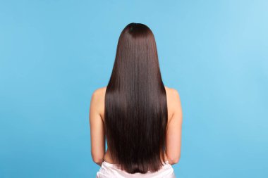 Açık mavi arkaplanda katman prosedüründen sonra güzel, pürüzsüz saçlı kadın.