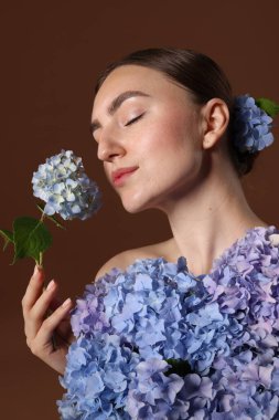 Kahverengi arka planda hortensiya çiçekleri olan güzel genç bir kadın.
