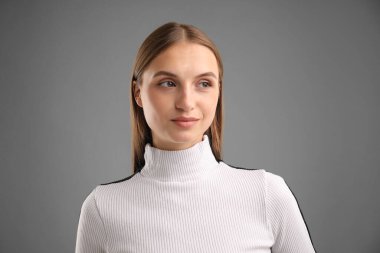Gri arkaplanda kendine güvenen bir kadının portresi