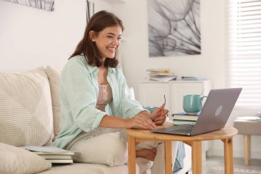 Öğrenci iyi bir sınav geçirdiği için mutlu. Tahta masada dizüstü bilgisayarla sonuçlanıyor.