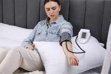 Kadın evdeki yatakta sphygmomanometre ile kalp atış hızını ve kan basıncını ölçüyor.