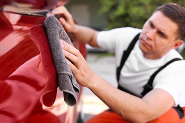 Dışarıdaki gri mikrofiber bez parçasıyla araba silen adam, yakın plan.