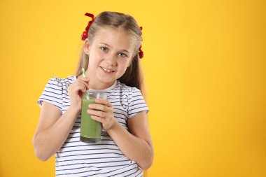 Meyve suyu ve turuncu arka planda saman içen küçük kız, mesaj için yer var.