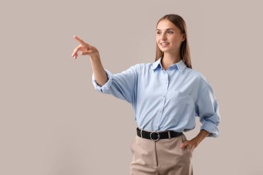 Güzel bir kadın arka plandaki bir şeyi işaret ediyor.