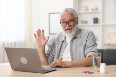 Üst düzey bir adam kapalı bir masada dizüstü bilgisayarla doktorla görüşüyor.