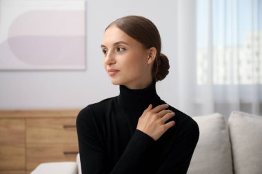 Evdeki kanepede oturan zarif kadın.