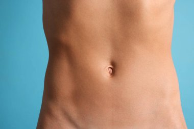 Açık mavi arka planda düz göbekli kadın, yakın plan.