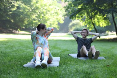 Genç adam profesyonel antrenörle dışarıda egzersiz yapıyor.