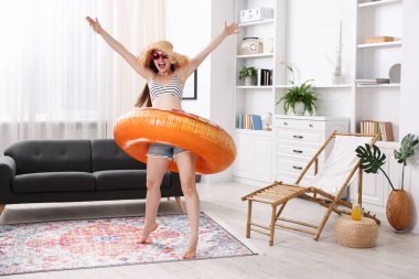 Güneş gözlüklü, hasır şapkalı, şişme yüzüklü mutlu kadın evde eğleniyor. Denizde tatilin hayalini kuruyorum.