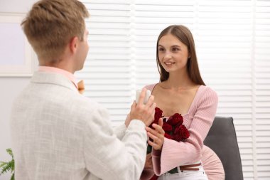 Nişan yüzüğü ve gül buketi olan bir adam mutlu kız arkadaşına evlenme teklif ediyor.