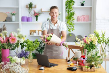 Dükkandaki ahşap masada çalışan bir buket çiçekli profesyonel çiçekçi.