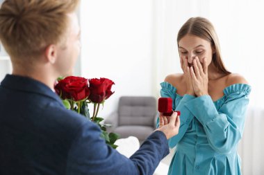 Nişan yüzüğü ve gül buketi olan bir adam mutlu kız arkadaşına evlenme teklif ediyor.