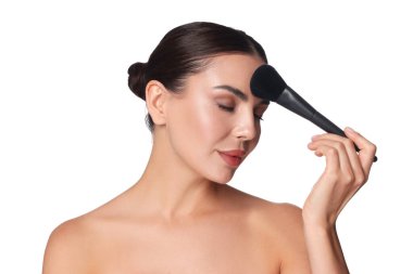 Güzel bir kadın beyaz arka planda fırçayla makyaj yapıyor.