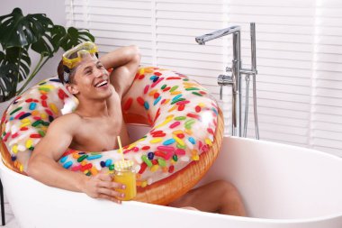 Dalgıç maskeli mutlu bir adam, bir kavanoz meyve suyu ve evdeki küvette soğuyan şişme bir yüzük. Denizde tatilin hayalini kuruyorum.