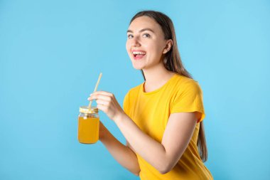 Serinletici bir içecek ve açık mavi arka planda saman taşıyan bir kadın.