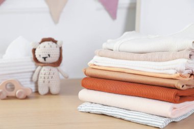 Temiz bebek kıyafetleri ve oyuncaklar ahşap masa içinde, yakın plan.