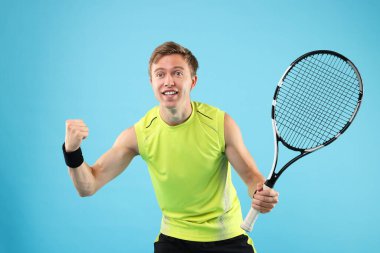 Açık mavi arka planda tenis raketi olan bir adam.