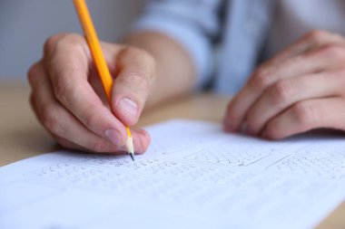 Öğrenci sınıfta çoklu seçim sınavı dolduruyor, yakın çekim. Sınavı geçmek