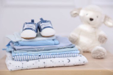 İçerideki ahşap masada temiz bebek kıyafetleri ve ayakkabılar yığını.