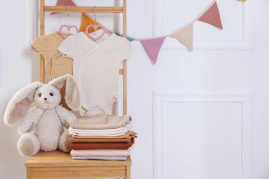 İçerideki ahşap şifoniyerde temiz bebek kıyafetleri ve oyuncak yığını. Mesaj atmak için yer.