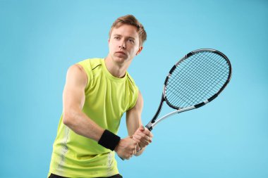 Açık mavi arka planda tenis raketi olan bir adam.