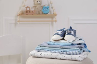 Temiz bebek kıyafetleri ve pouf kapalı yerde ayakkabı yığını, mesaj için yer