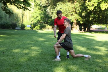 Genç adam dışarıda profesyonel antrenörle egzersiz yapıyor. Metin için boşluk