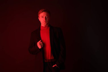 Siyah arka planda neon ışıklarda takım elbise giyen yakışıklı bir adamın portresi.